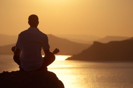 man sitting in mindfulness meditation doing shadow work in front of sunset