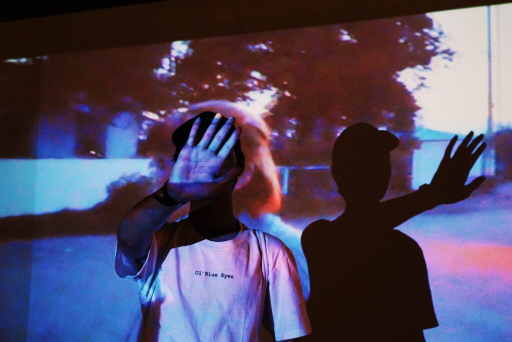man holds up hand to projector projecting shadow onto world