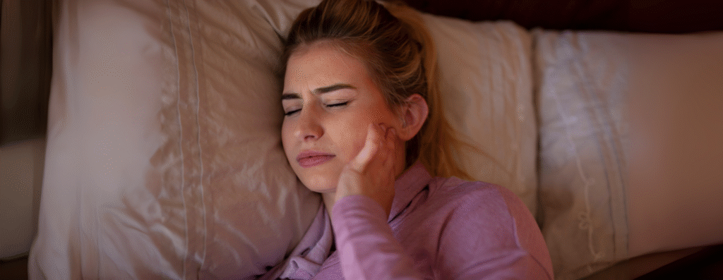 A woman having discomfort from jaw pain during sleep